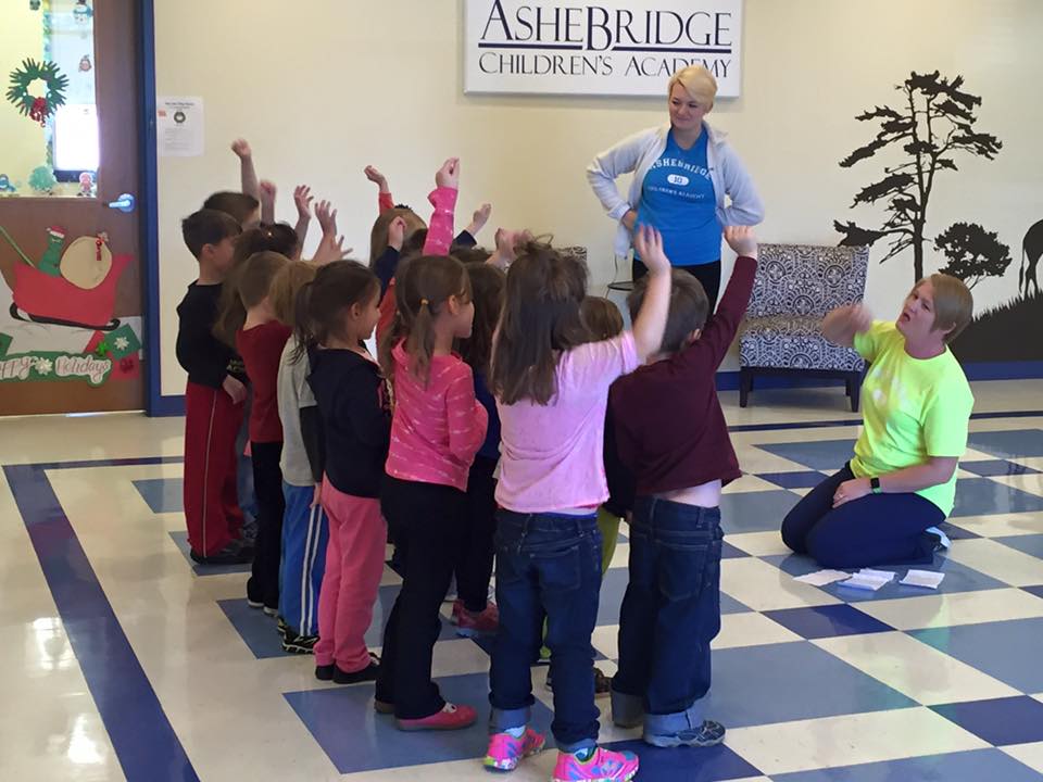 Children raising hands, to answer teachers question, at a Preschool & Daycare/Childcare Center serving Apex & Fuquay-Varina, NC