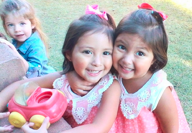 Happy cute little twin girls enjoying each others company playing Happy young little girls working with art project at a Preschool & Daycare/Childcare Center serving Apex & Fuquay-Varina, NC