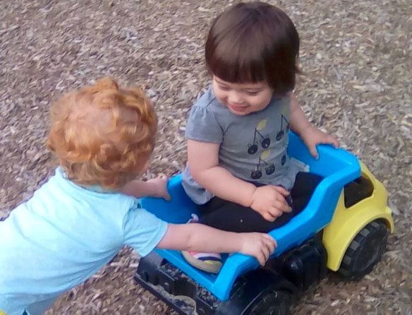 Young little boys playing on the back of a toy truck at a Preschool & Daycare/Childcare Center serving Apex & Fuquay-Varina, NC