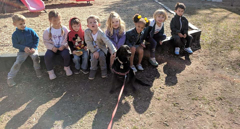 Children sitting with a dog in the middle at a Preschool & Daycare/Childcare Center serving Apex & Fuquay-Varina, NC