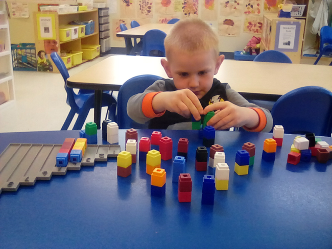 Kid boy playing with educational building blocks at a Preschool & Daycare/Childcare Center serving Apex & Fuquay-Varina, NC
