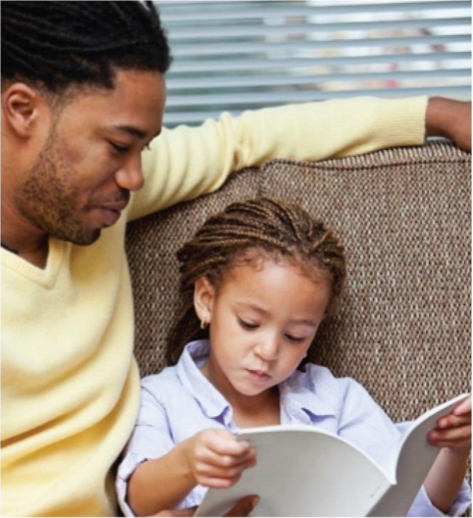 African american dad and young little daughter reading an educational book at a Preschool & Daycare/Childcare Center serving Apex & Fuquay-Varina, NC