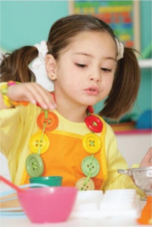 Beautiful little young girl on a ponytail wearing colorful shirt playing with educational toys at a Preschool & Daycare/Childcare Center serving Apex & Fuquay-Varina, NC