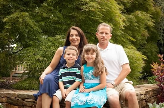 Family picture of happy parents and little kids on the garden at a Preschool & Daycare/Childcare Center serving Apex & Fuquay-Varina, NC