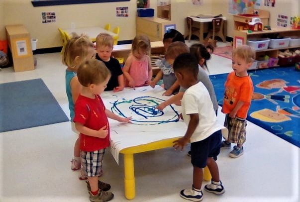 Group of toddlers doing hand painting on the table at a Preschool & Daycare/Childcare Center serving Apex & Fuquay-Varina, NC