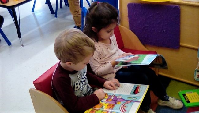 Two toddlers reading educational book for early literacy at a Preschool & Daycare/Childcare Center serving Apex & Fuquay-Varina, NC